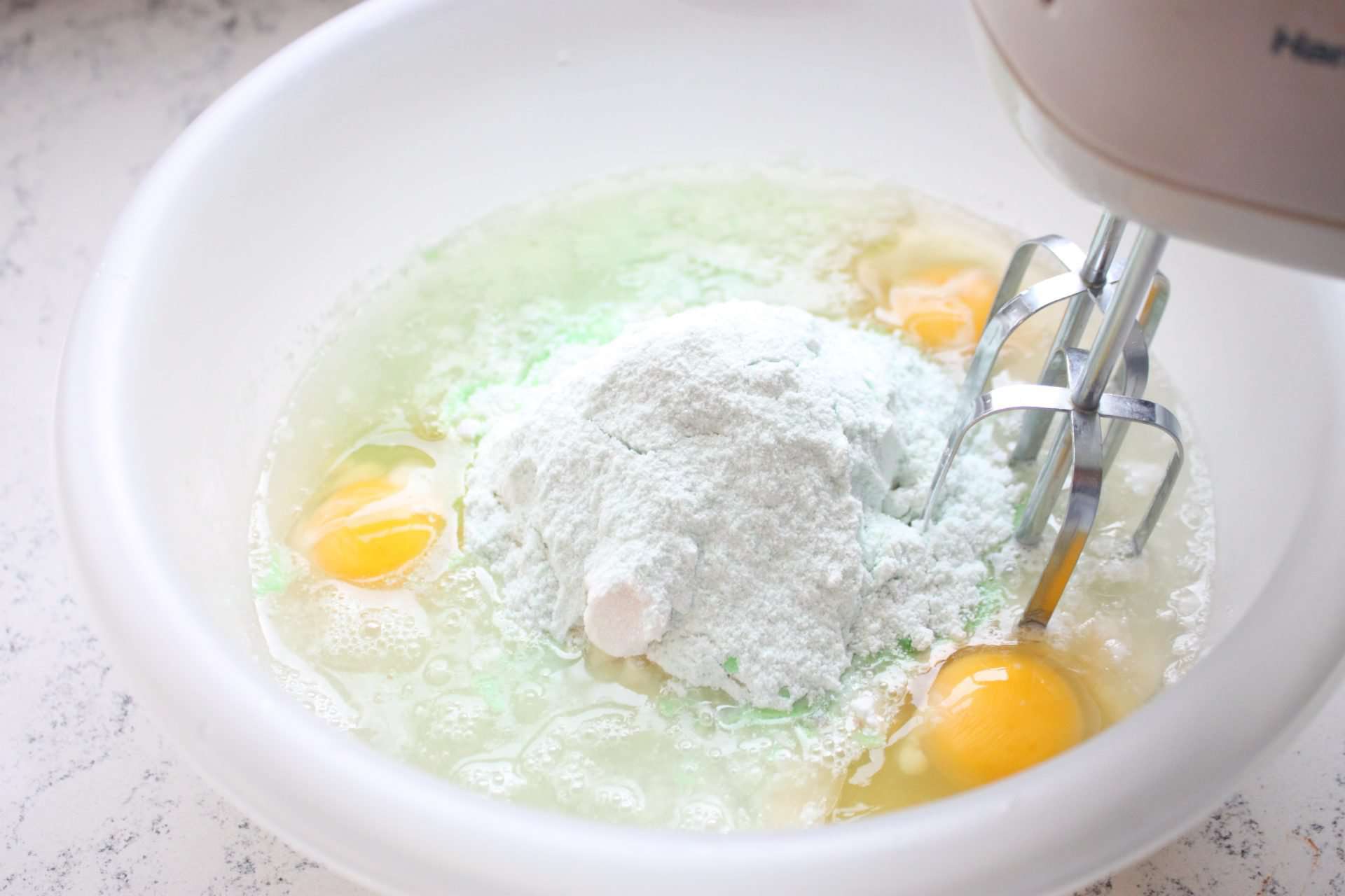Pistachio and Coconut Pudding Cake Ingredients in Bowl being Mixed with a Mixer