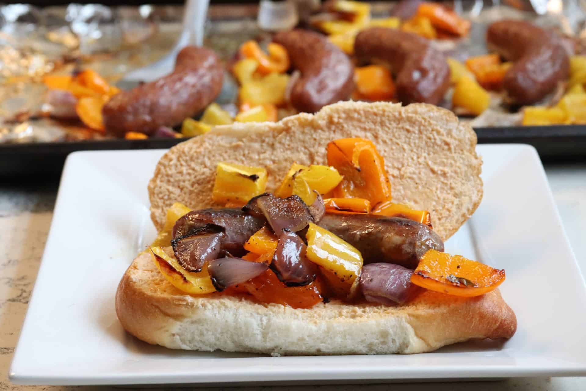 Italian sausage hoagie sandwiches on a plate with roasted peppers and onions piled into soft hoagie rolls.