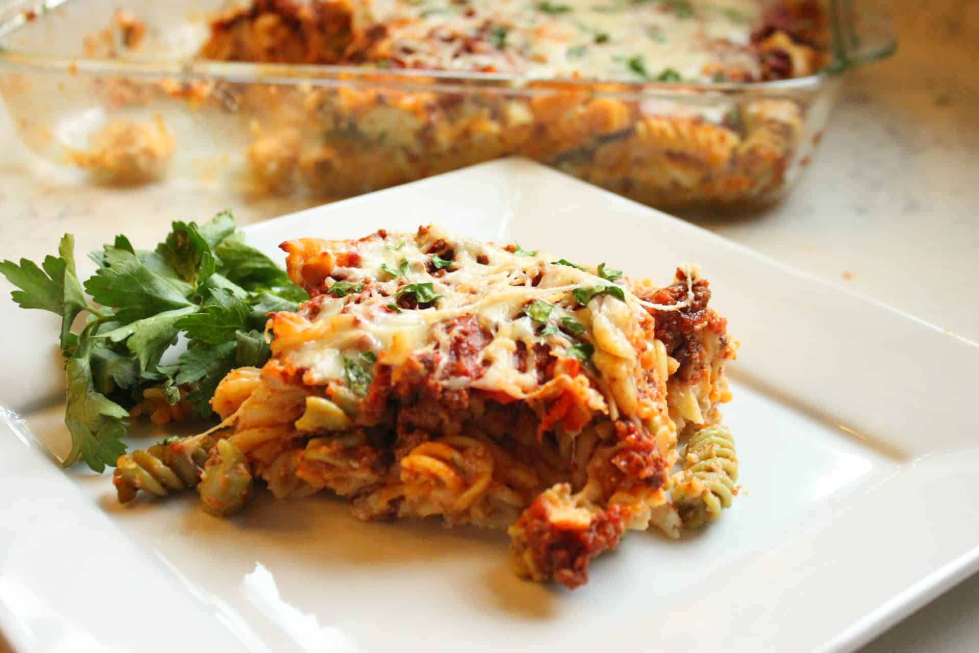 A plated serving of freezer-friendly cheesy baked ziti with herbs, served alongside fresh parsley for a comforting meal.