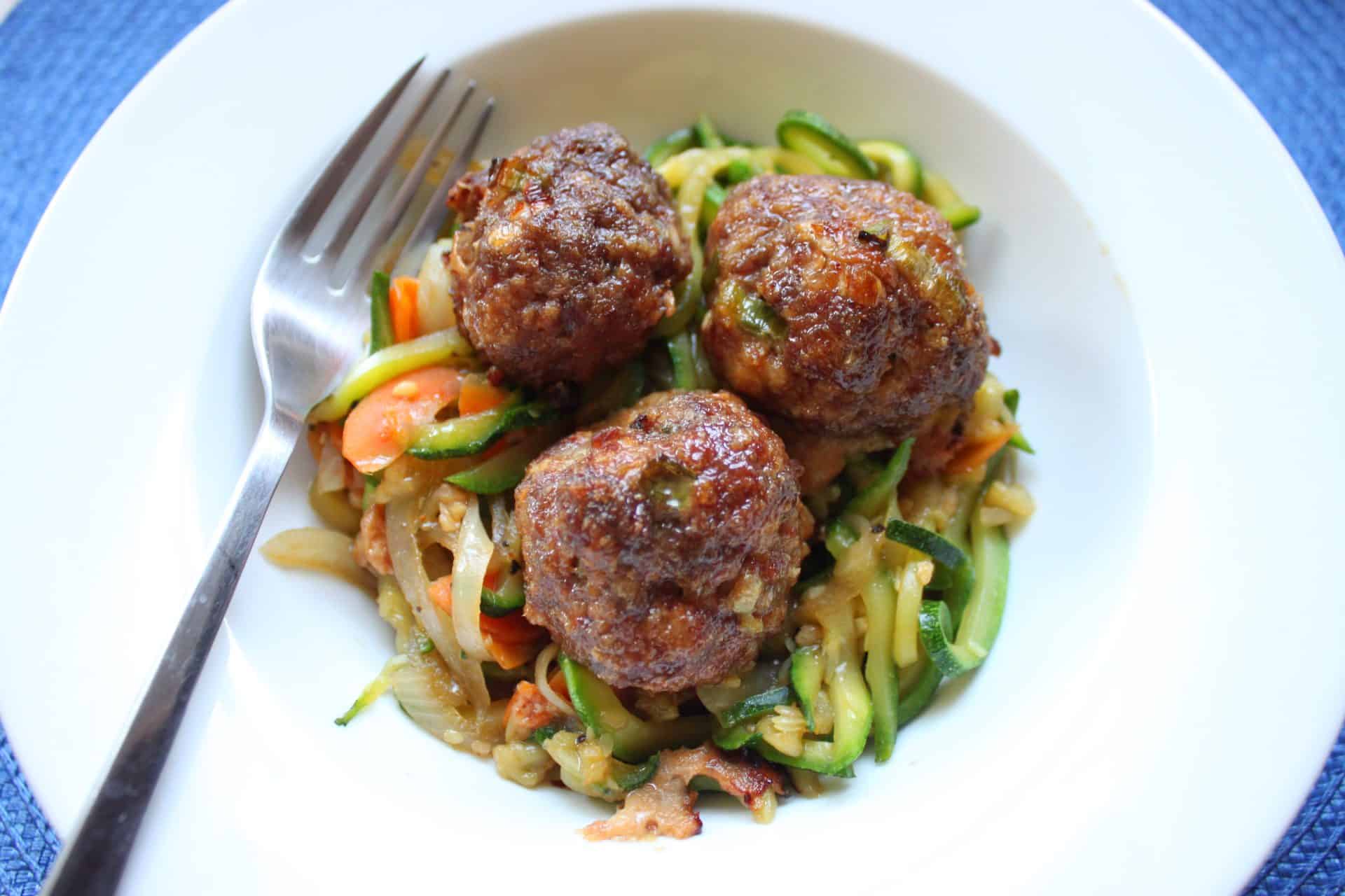 Korean Meatballs with Stir-Fry Zucchini Noodles: A Delicious Twist on Dinner 8 Full serving of Korean meatballs with stir-fry zucchini noodles in a bowl with vibrant vegetables and savory glaze.