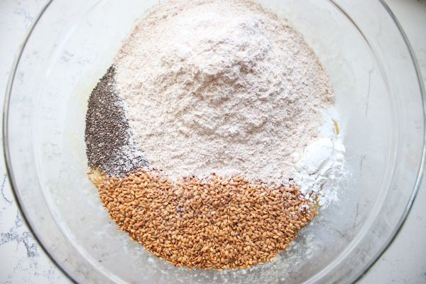 Whole wheat flour, chia seeds, flax seed, baking powder, and salt measured into a bowl to form the dry base of healthy blueberry bran muffins.