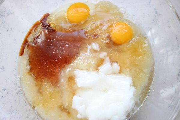 Egg, honey, applesauce, vanilla, and melted coconut oil in a bowl to mix as the wet ingredients for healthy blueberry bran muffins.