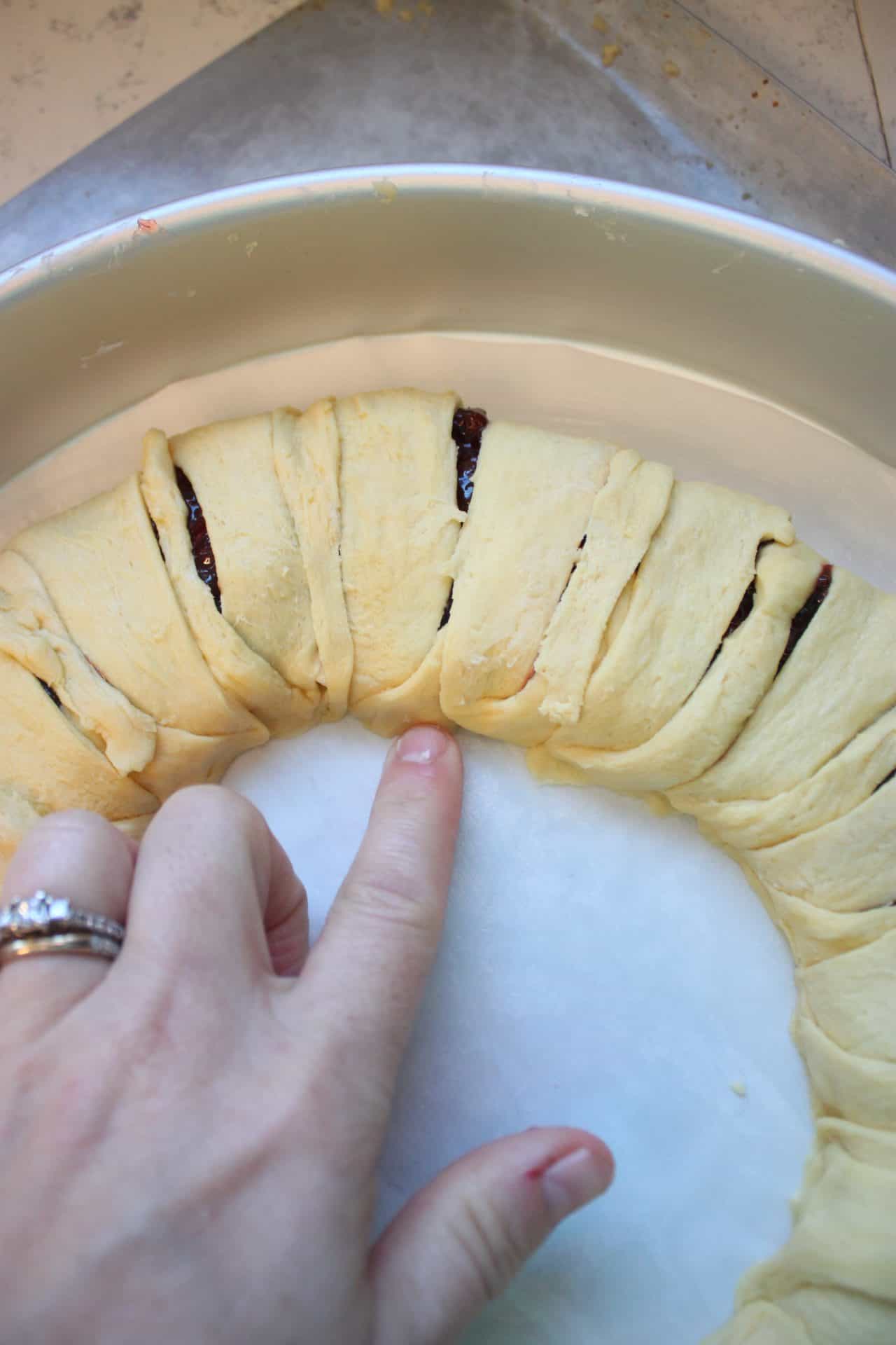 Raspberry Almond Danish: A Festive Breakfast Treat 7 Hands press down dough to seal the raspberry almond Danish and prevent filling from leaking during baking.