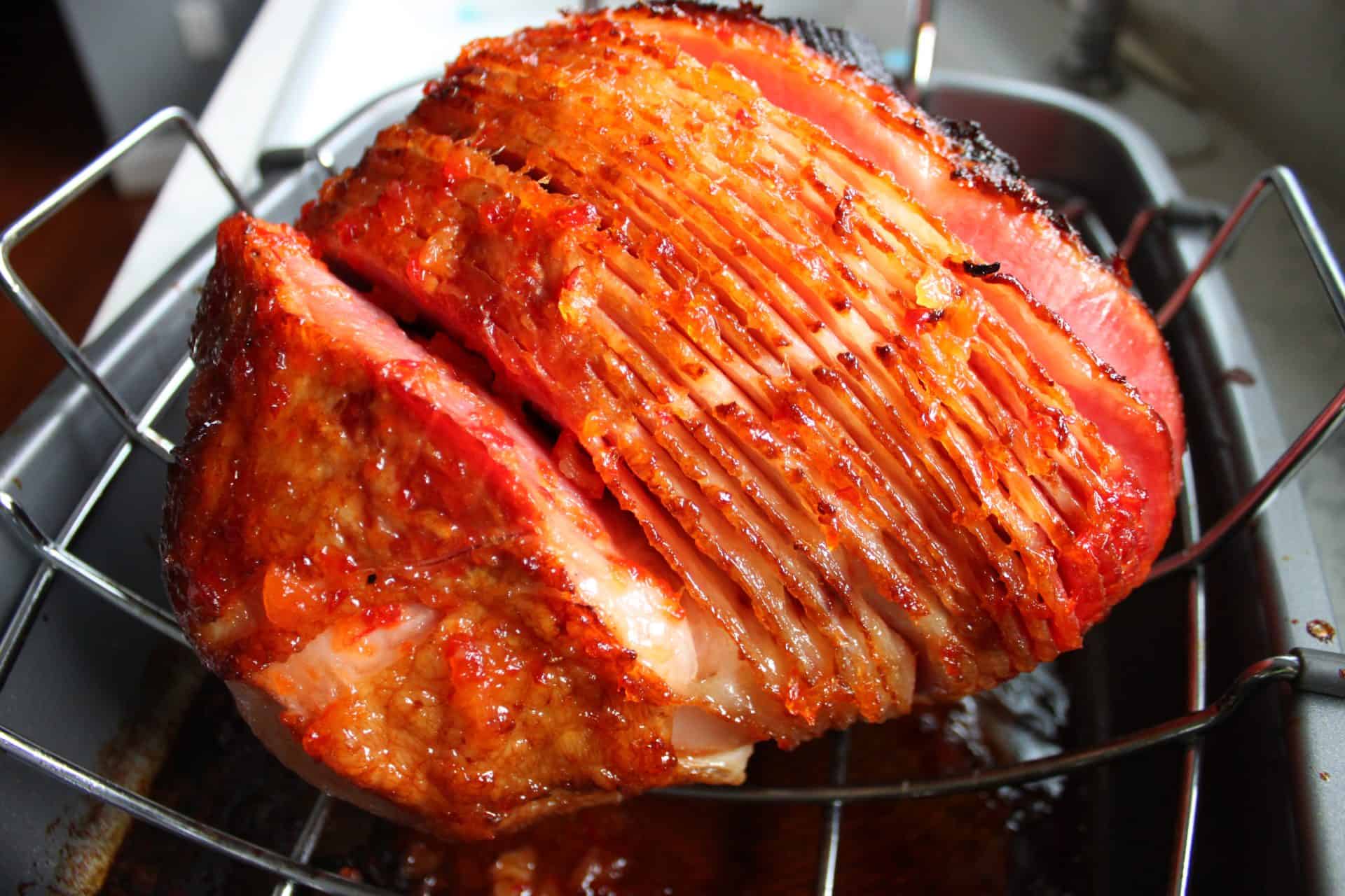 Unforgettable Holidays Start with This Prosecco and Pineapple Glazed Ham 4 Spiral-cut ham roasting in a pan, edges caramelizing as the Prosecco and pineapple glaze bakes into the meat.