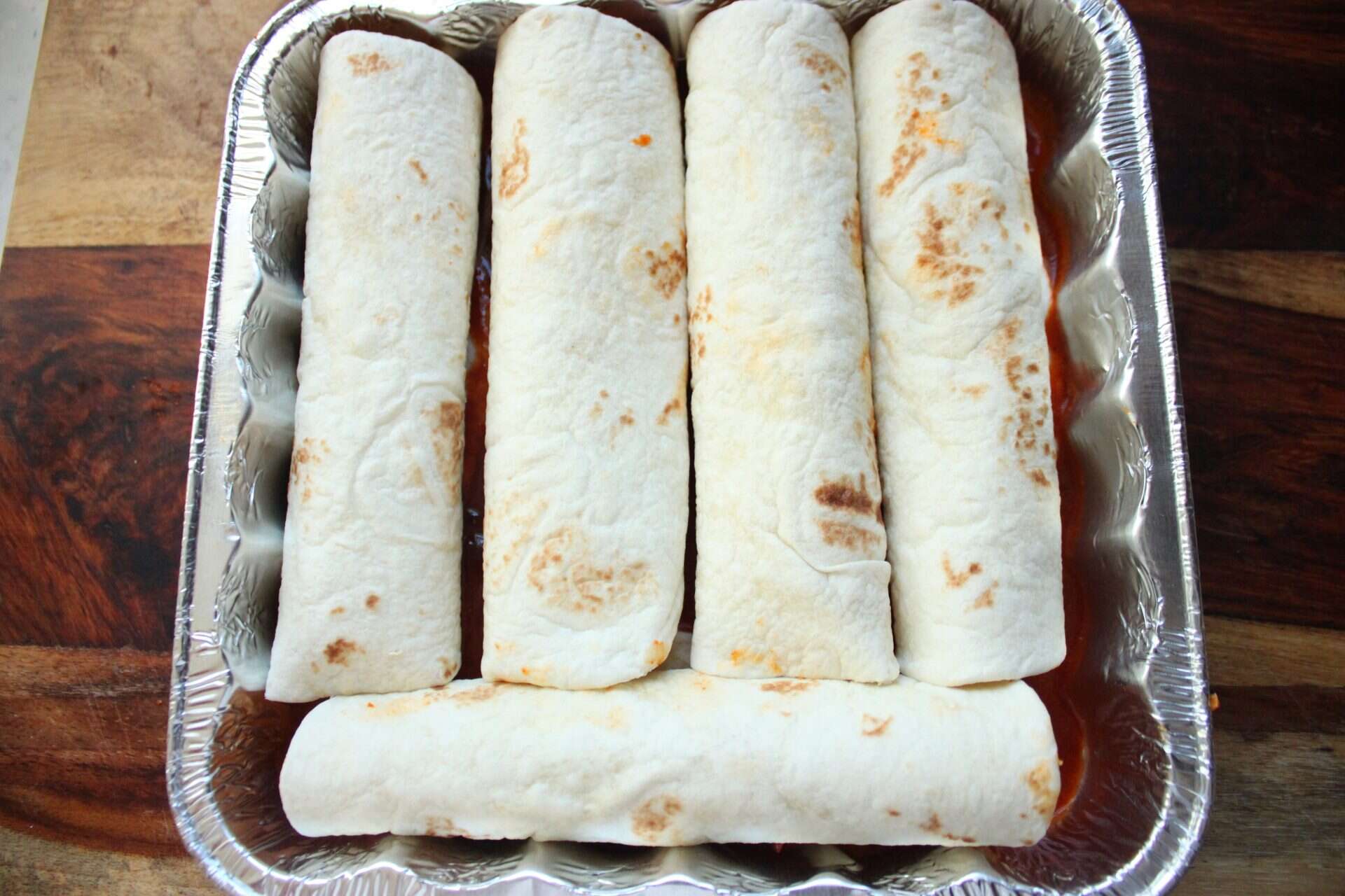 Rolled flour tortillas filled with spicy chicken mixture, ready for the oven in this comforting enchilada recipe.