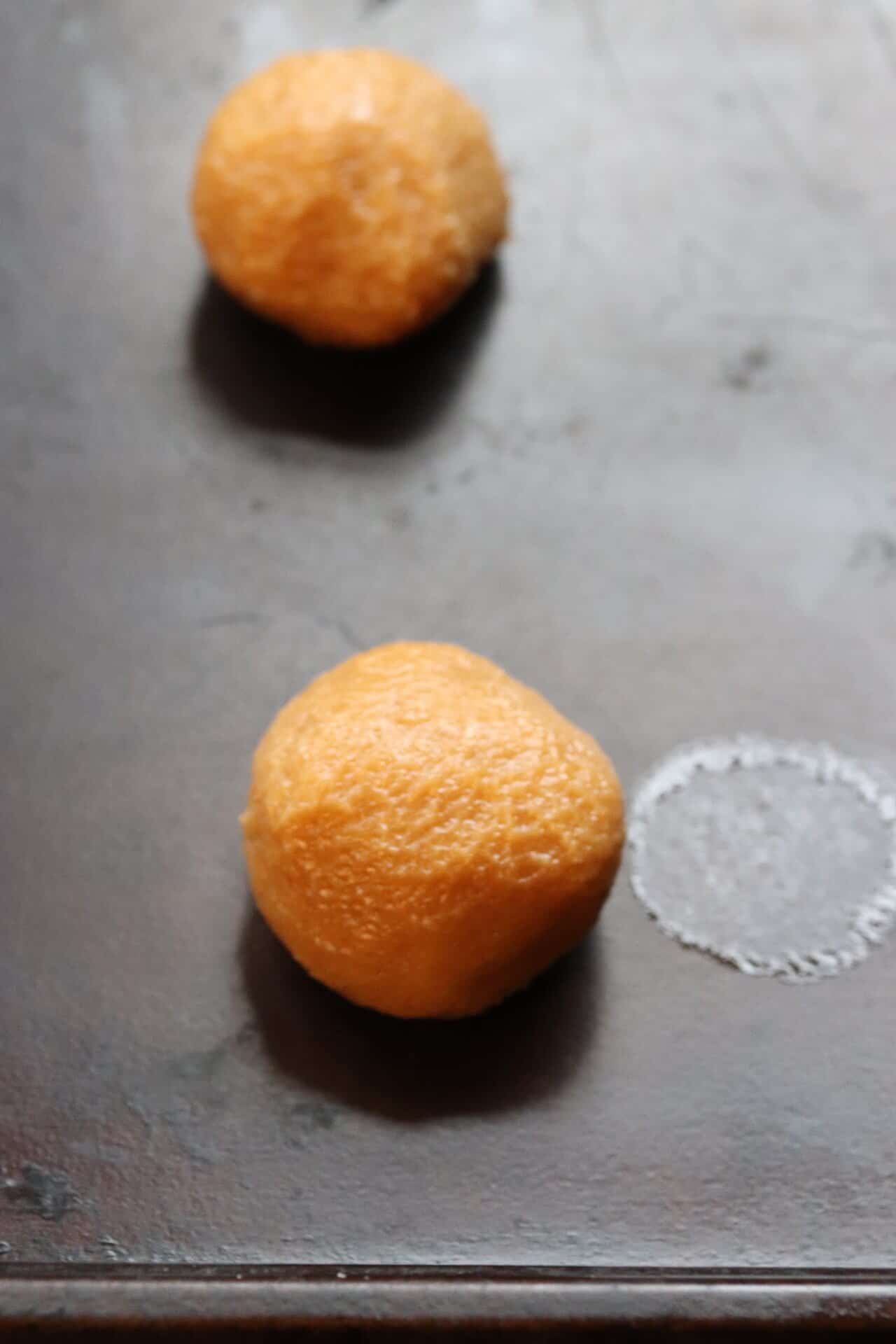 Peanut butter cookie dough rolled into smooth balls on a baking sheet, the first shaping step in making 3 Ingredient Peanut Butter Cookies.