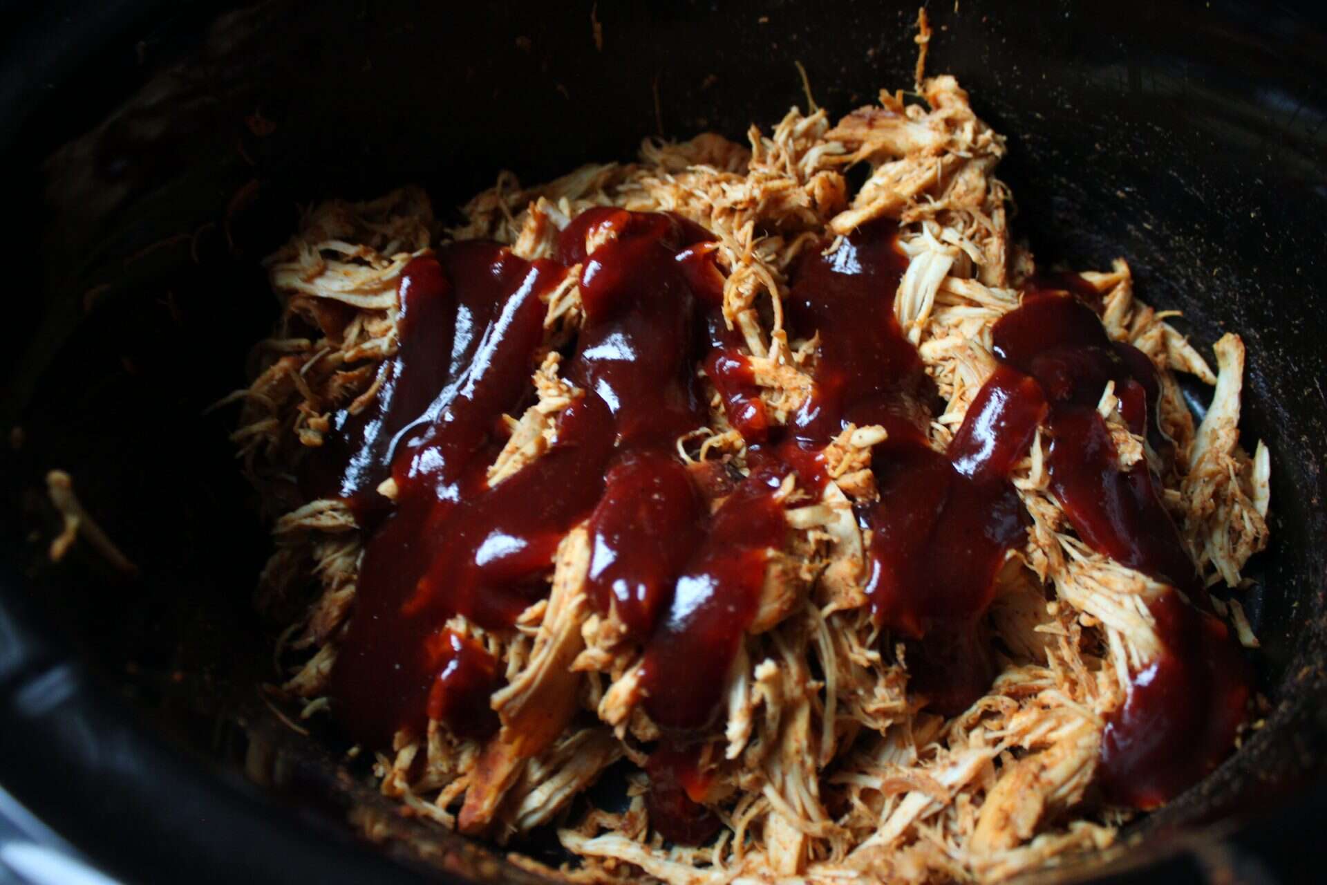 Crockpot BBQ Chicken Tacos with a Smoky Slow Cooker Blend 4 Cooked chicken shredded in the Crockpot and topped with a generous drizzle of BBQ sauce, ready to be used in Crockpot BBQ Chicken Tacos.