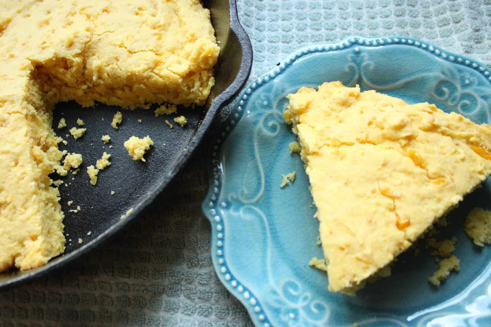 Skillet Cornbread with Creamed Corn on a Blue Plate and in a Black Cast Iron Skillet