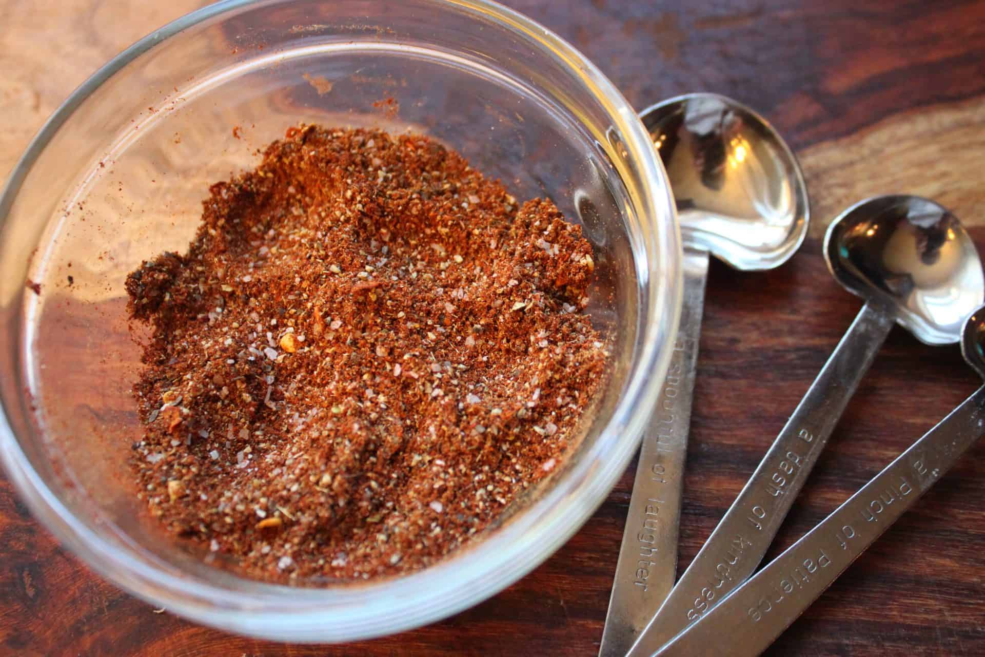 A bowl filled with a homemade spice mix of chili powder, cumin, and garlic powder, key ingredients for spicy chicken enchiladas.