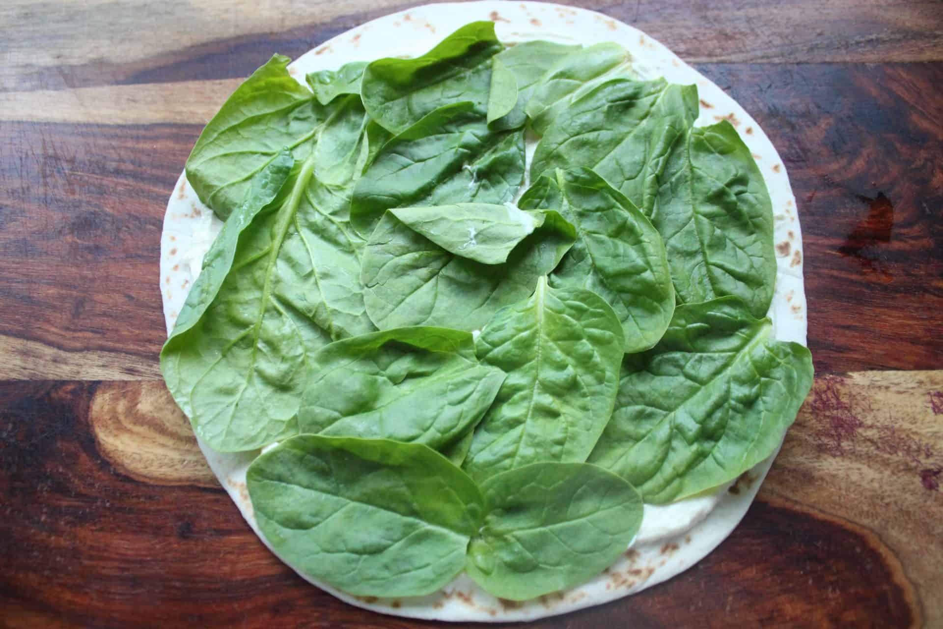 7-Minute Roast Beef Tortilla Wraps for Effortless Meals & Parties 4 Tortilla on a Wood Counter with Spinach Spread Out on the Tortilla