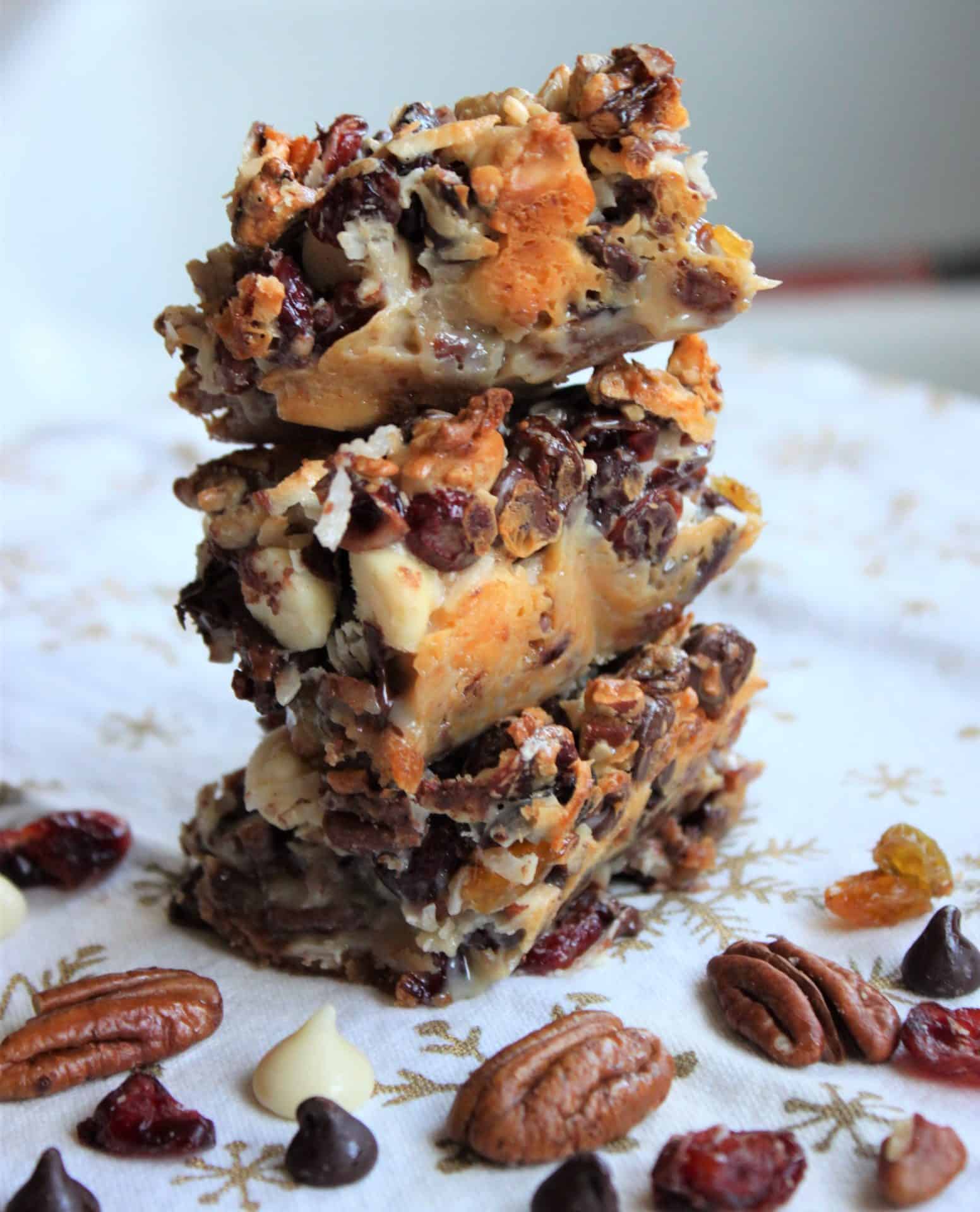 A stacked pile of Coconut Pecan Bars showing the gooey layers of nuts, coconut, and chocolate over the graham cracker crust.