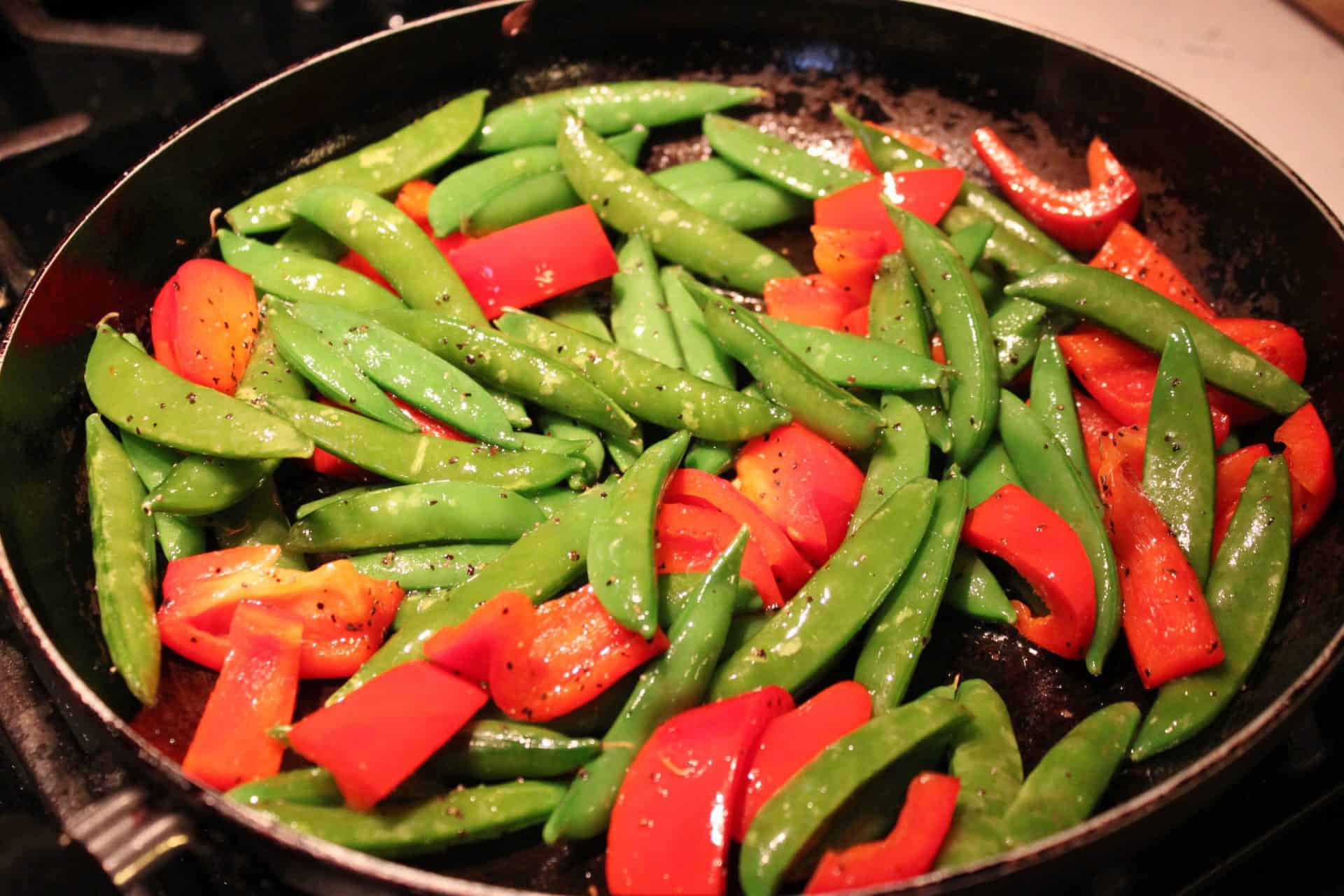 Mouthwatering Dijon Salmon and Sautéed Snap Peas: An Unforgettable Meal! 7 Stir Frying Bell Peppers and Snap Peas in a Black Pan on the Stove