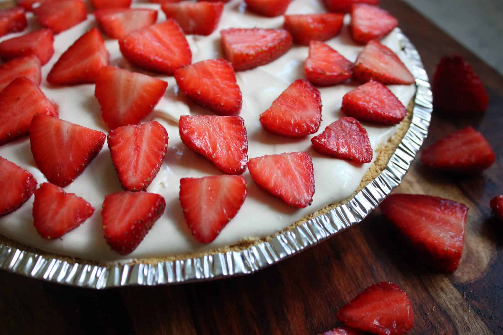 Easy No-Bake Strawberry Cheesecake 10 Strawberry Cheesecake, with Strawberry Topping, Sitting on a Wooden Cutting Board