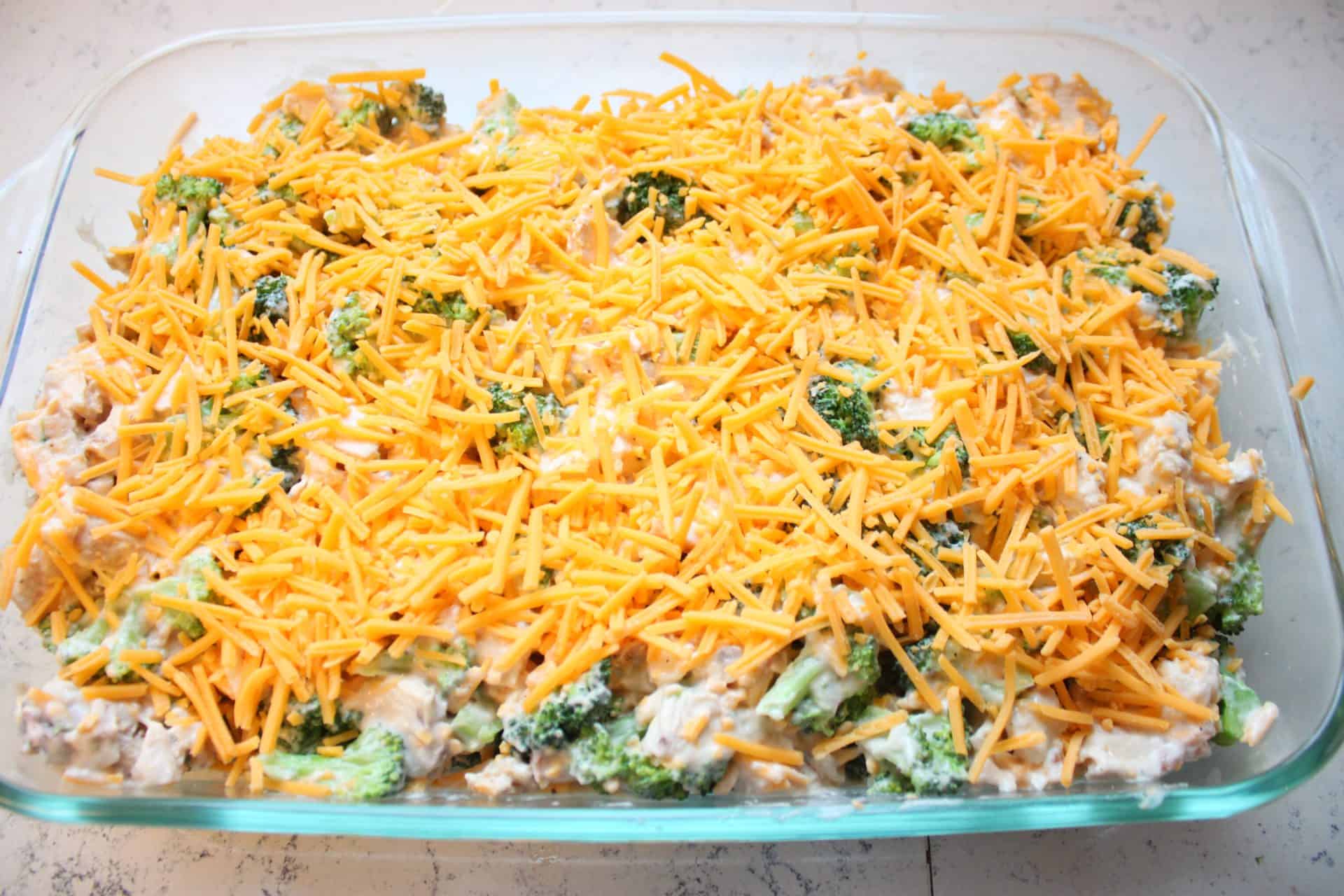 Delicious 30-Minute Chicken and Broccoli Casserole for Busy Nights 5 Unbaked casserole mixture topped with shredded cheddar cheese, ready to go into the oven to finish the 30 minute chicken and broccoli casserole.