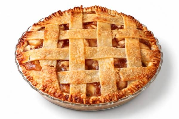 Apple pie at a three-quarter angle showing its golden lattice crust and shallow clear glass dish.