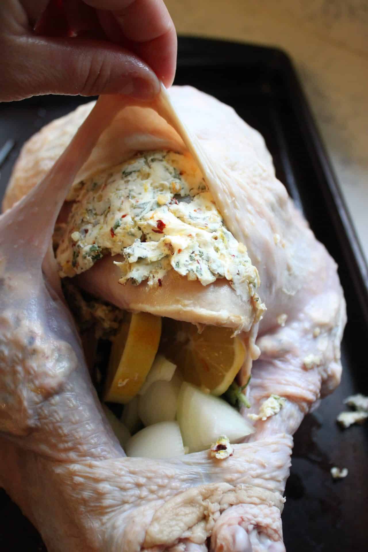 Foolproof 3-Step Tuscan-Style Roasted Turkey for the Holidays 10 Herbed butter barrier being spread under the skin of Tuscan-style roasted turkey, ensuring juicy, flavorful meat.