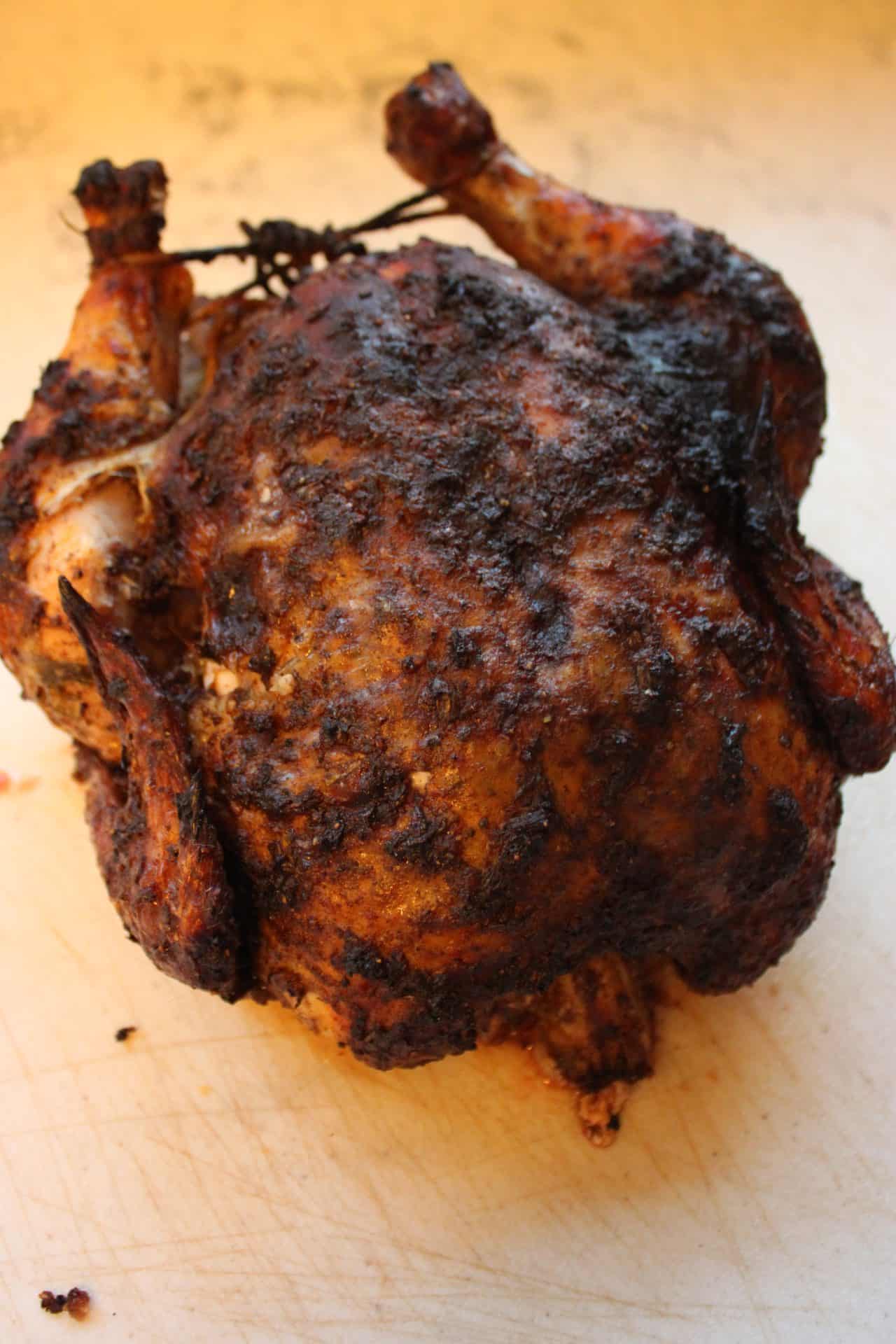 The Easy Roasted Jerk Chicken rests on a plate, ready to be carved after baking, showing off its juicy, tender meat.
