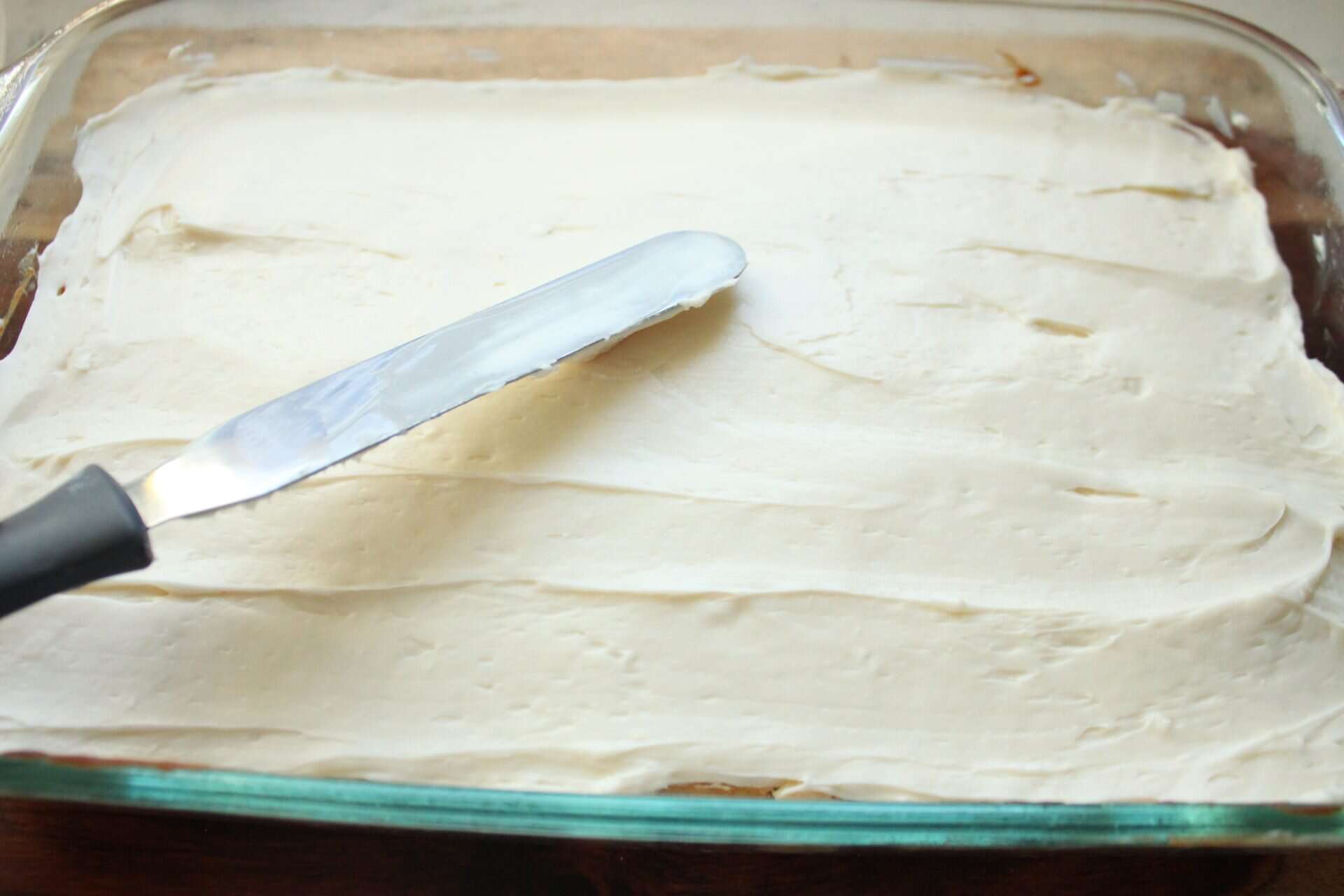 Easy Recipe for Copycat Starbucks White Chocolate Cranberry Bliss Bars 3 A spatula spreads cream cheese frosting evenly over Starbucks white chocolate cranberry bliss bars for a smooth and sweet layer.